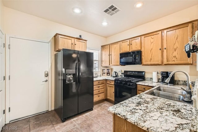 kitchen featuring sink, light tile patterned floors, light stone counters, and black appliances