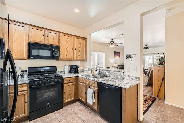 kitchen featuring light tile patterned flooring, sink, light stone counters, kitchen peninsula, and black appliances