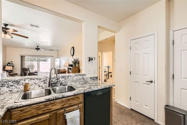 kitchen with light stone countertops, dishwasher, sink, and dark tile patterned flooring