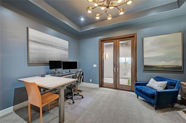 carpeted home office with a raised ceiling, a chandelier, and french doors