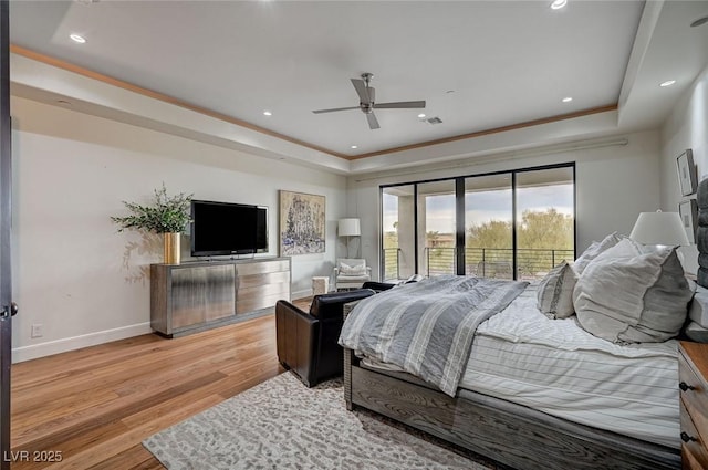 bedroom featuring ceiling fan, a tray ceiling, light hardwood / wood-style flooring, and access to outside