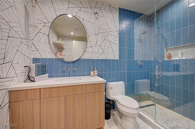 bathroom featuring tile walls, vanity, an enclosed shower, toilet, and tile patterned floors