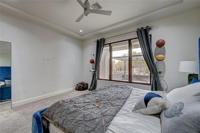 carpeted bedroom featuring ceiling fan and a tray ceiling