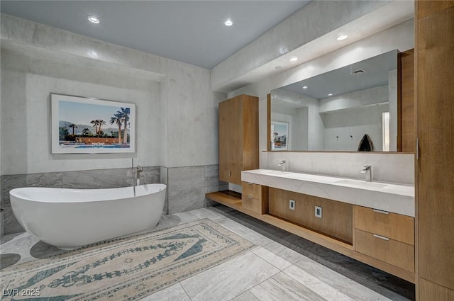 bathroom with vanity, a bath, and tile walls