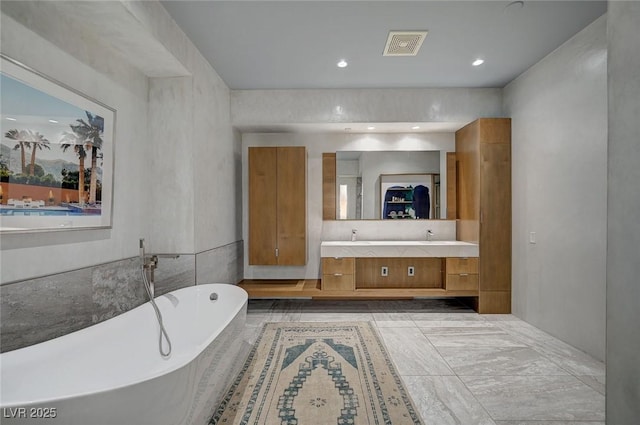 bathroom featuring a relaxing tiled tub and vanity