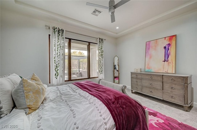 carpeted bedroom featuring ceiling fan and a tray ceiling