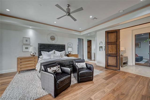 bedroom featuring ceiling fan, a raised ceiling, and light hardwood / wood-style floors