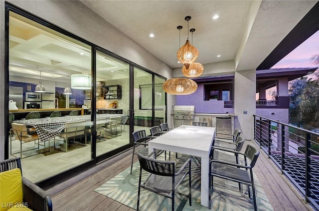 balcony at dusk featuring an outdoor kitchen, exterior bar, and grilling area