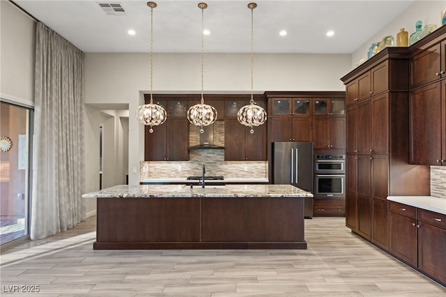 kitchen with light stone counters, stainless steel appliances, and dark brown cabinets