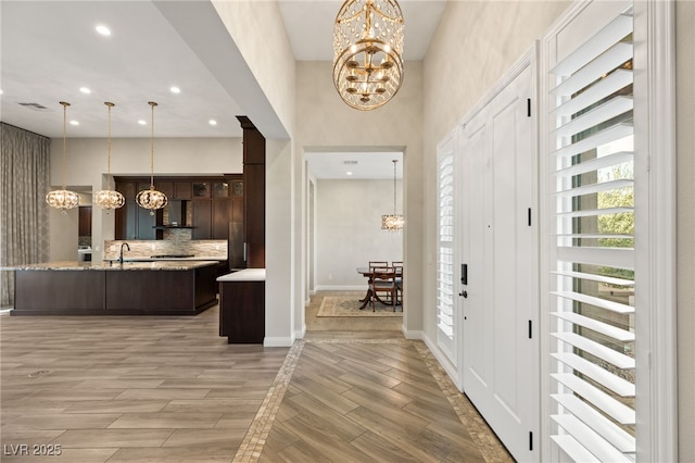 foyer featuring a notable chandelier, sink, and light wood-type flooring