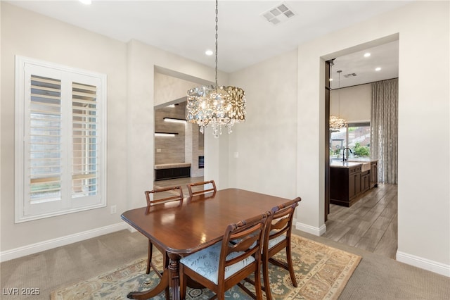 dining area with light carpet, sink, and an inviting chandelier