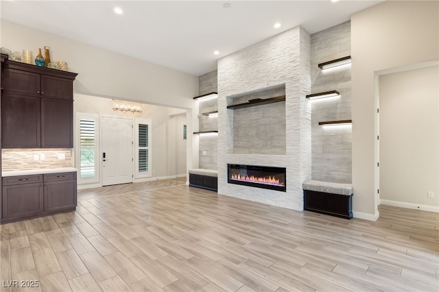 10179 Emerald Sunset Ct, Las Vegas, NV 89148 - unfurnished living room featuring baseboards, a fireplace, light wood-type flooring, a chandelier, and recessed lighting