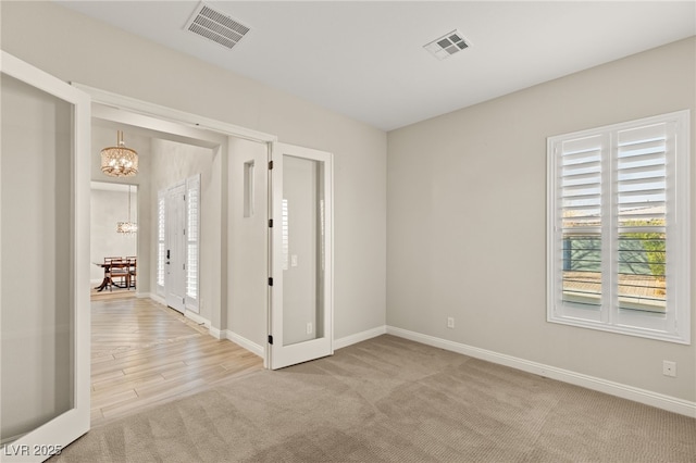 unfurnished room featuring an inviting chandelier and light carpet