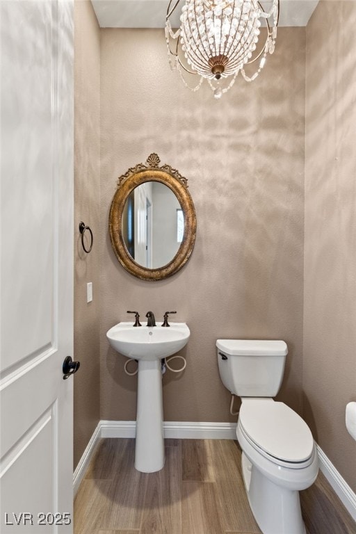 bathroom with an inviting chandelier, hardwood / wood-style floors, and toilet