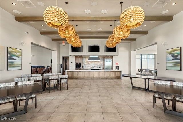 kitchen with an inviting chandelier, beamed ceiling, oven, and wall chimney exhaust hood