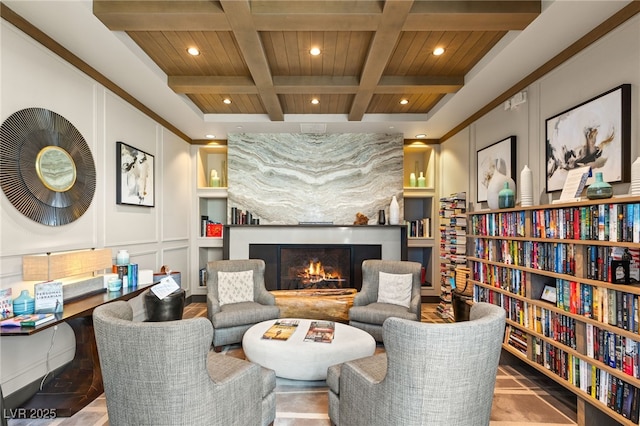 living area with coffered ceiling, beam ceiling, built in features, and a large fireplace