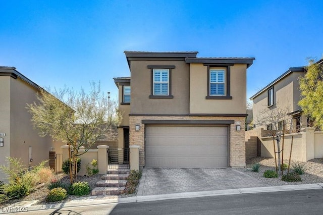 view of front of home featuring decorative driveway, an attached garage, fence, and stucco siding