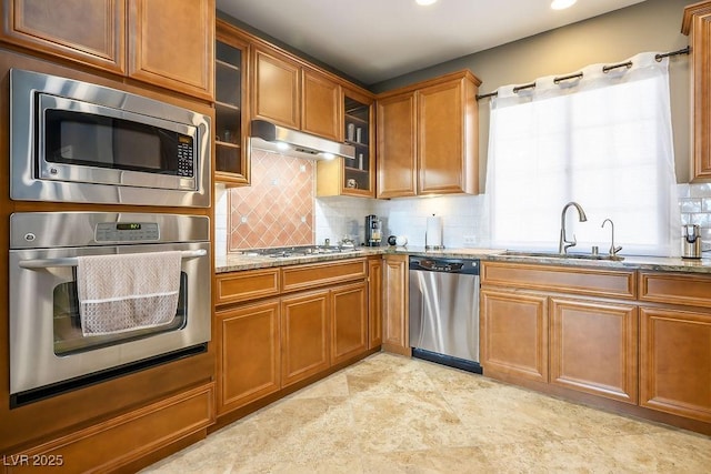 kitchen featuring tasteful backsplash, stainless steel appliances, light stone countertops, and sink