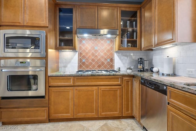 kitchen featuring decorative backsplash, light stone countertops, and appliances with stainless steel finishes