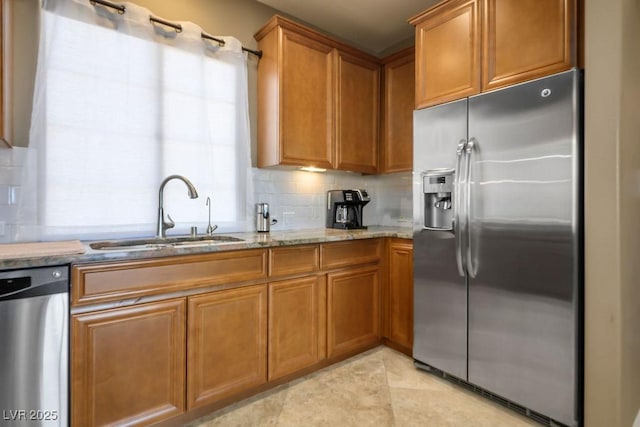 kitchen with tasteful backsplash, light stone countertops, appliances with stainless steel finishes, and sink