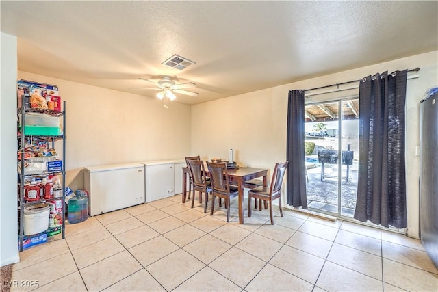 tiled dining space with a textured ceiling and ceiling fan