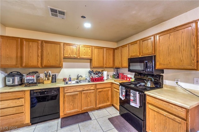 kitchen featuring sink, black appliances, and light tile patterned flooring