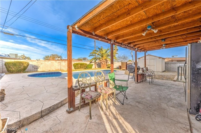 view of patio featuring a fenced in pool and a shed