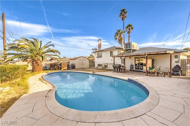 view of swimming pool featuring a patio, cooling unit, and a storage shed