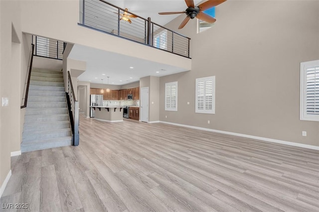 unfurnished living room featuring ceiling fan, plenty of natural light, and light hardwood / wood-style floors