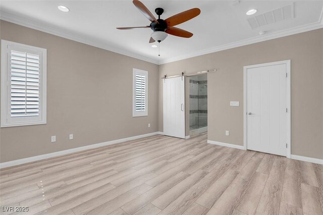 empty room with ornamental molding, a barn door, ceiling fan, and light hardwood / wood-style flooring