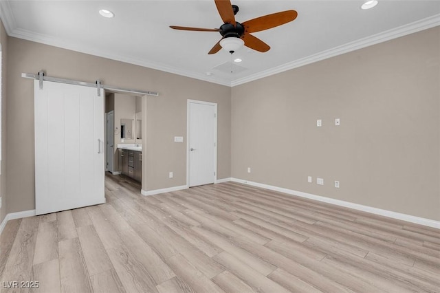 unfurnished bedroom with ensuite bath, ornamental molding, a barn door, and light wood-type flooring