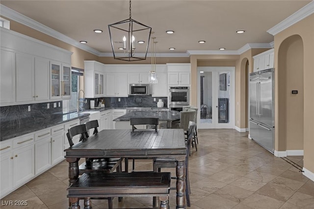 kitchen with sink, dark stone countertops, pendant lighting, stainless steel appliances, and white cabinets