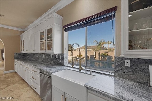 kitchen with white cabinetry, dishwasher, decorative backsplash, crown molding, and light stone countertops