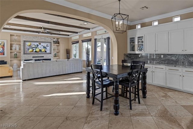 dining area with crown molding, built in shelves, ceiling fan with notable chandelier, and beamed ceiling