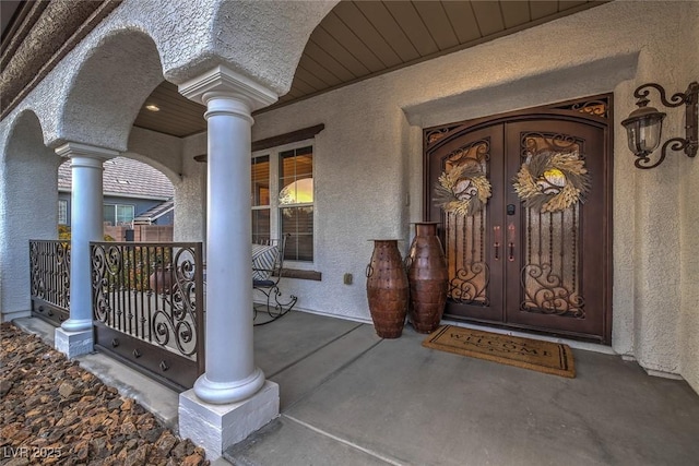 view of exterior entry featuring french doors and a porch