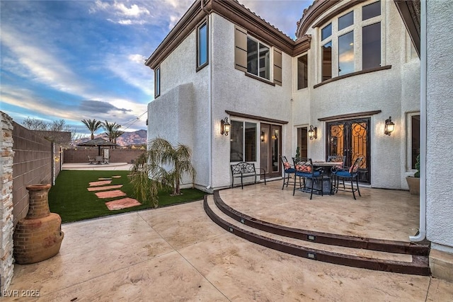 back house at dusk with a patio and french doors