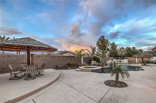 patio terrace at dusk with a swimming pool with hot tub