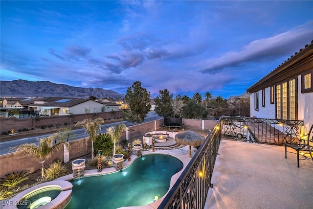 pool at dusk featuring an in ground hot tub, pool water feature, and a mountain view