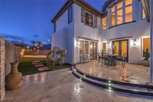 back house at dusk with a patio and french doors