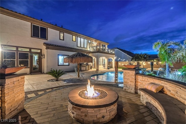 view of patio featuring a balcony, an outdoor fire pit, and a fenced in pool