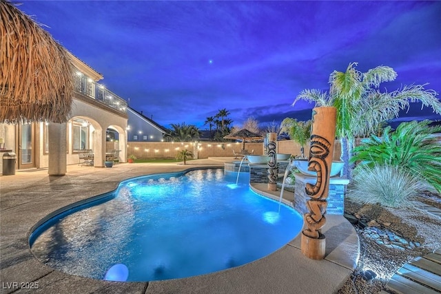 pool at dusk featuring pool water feature and a patio area