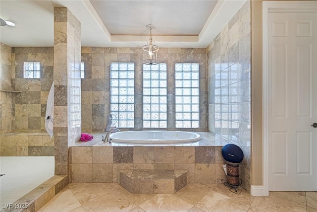 bathroom featuring tile walls, a raised ceiling, and a healthy amount of sunlight