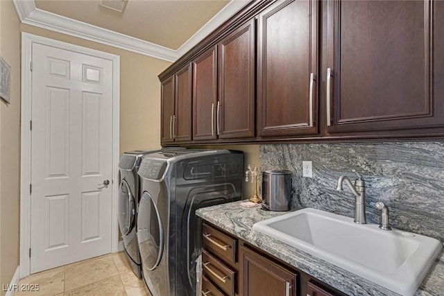 laundry room featuring sink, crown molding, washer and clothes dryer, light tile patterned floors, and cabinets