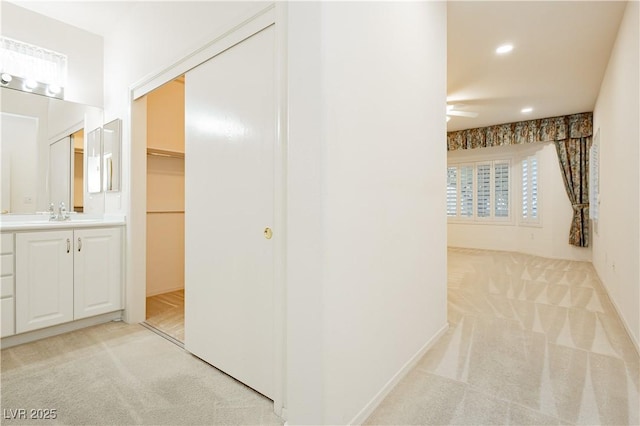 corridor with sink and light colored carpet