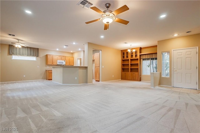 unfurnished living room with light carpet and ceiling fan with notable chandelier