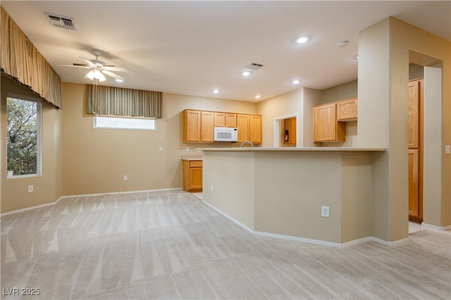 kitchen featuring ceiling fan, light carpet, light brown cabinetry, and kitchen peninsula