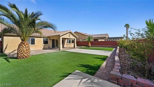 rear view of house with a patio and a lawn