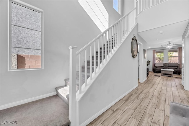 stairs featuring wood-type flooring, ceiling fan, and a high ceiling