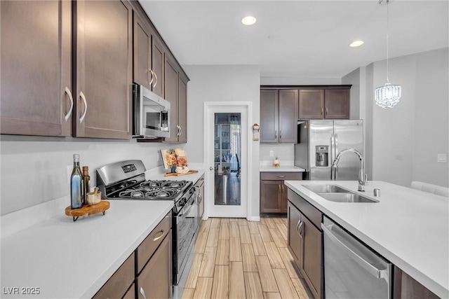 kitchen featuring hanging light fixtures, appliances with stainless steel finishes, sink, and dark brown cabinetry