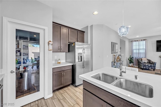 kitchen featuring pendant lighting, sink, stainless steel fridge, an inviting chandelier, and dark brown cabinets